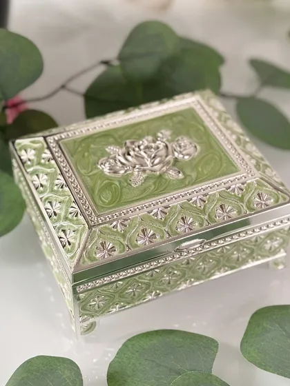A closer look at the silver rose motif on the green enamel box. The intricate craftsmanship and delicate color make it a truly special keepsake holder.