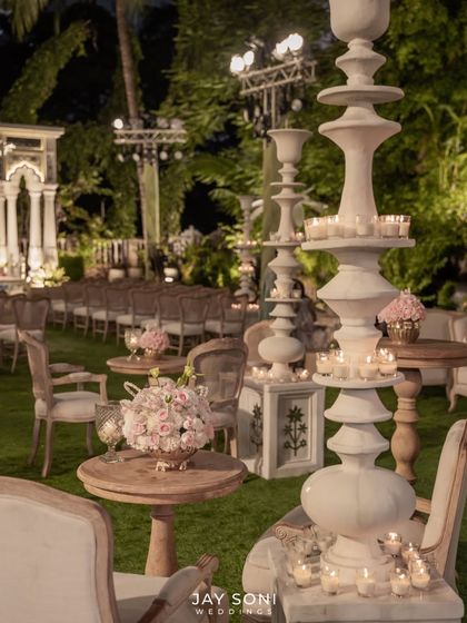 Tall, sculptural candle stands create a dramatic and romantic effect, illuminating the lounge seating and adding to the magical ambiance of this nighttime wedding ceremony.