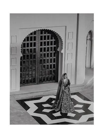 A timeless black and white portrait of the bride at The Oberoi Udaivilas, using the palace's arches and geometric floor to create a dramatic composition.