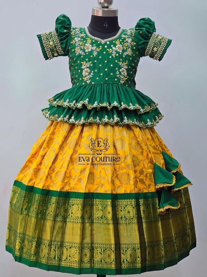 A designer take on the classic yellow and green combination. This lehenga features a tiered peplum blouse with intricate maggam work and a traditional yellow silk skirt.