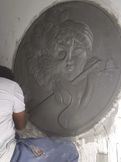 Here I am giving the final touches to a large, circular Krishna mural. This shows the hands-on nature of my work and the focus required for every detail.