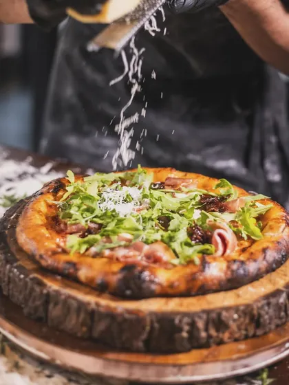 A final grating of fresh Parmesan cheese over our Prosciutto and Fig pizza adds a salty kick to balance the sweet and peppery flavors.