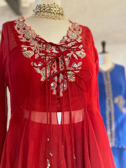 A sheer red peplum top with intricate embroidery and a tie-up detail at the front, a perfect fusion of modern and traditional.