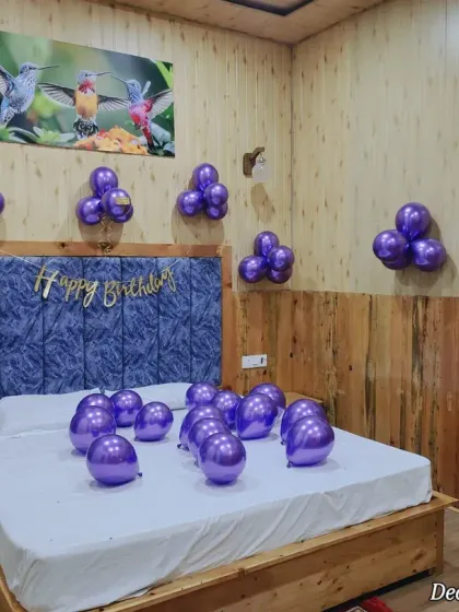 A clean and simple birthday surprise. The metallic purple balloon clusters add a pop of color and fun to this wood-paneled room, proving that even minimal decor can make a big impact.