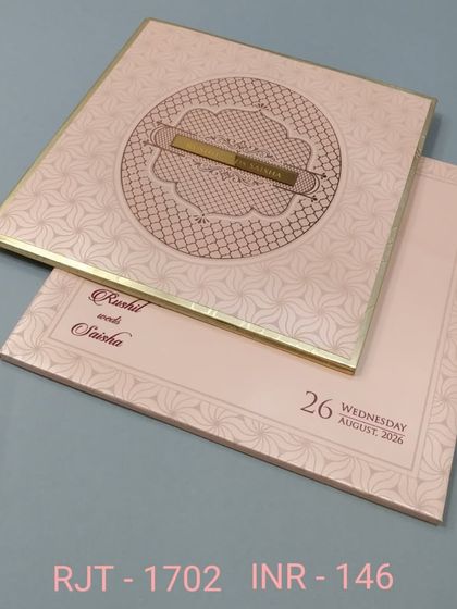 A beautiful invitation in a soft, blush pink with a geometric pattern and a central nameplate. The design is modern, elegant, and chic.