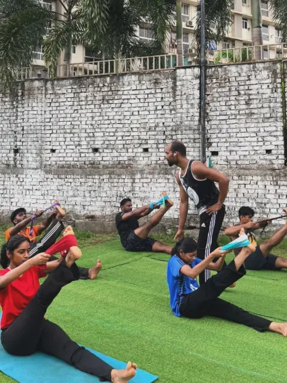 A coach leading a group through hamstring stretches with bands. We use tools to help our members achieve a deeper, more effective stretch.