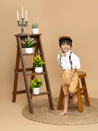 A charming smile from a dapper little boy. This classic portrait uses a simple, neutral background to highlight his adorable outfit and happy expression.