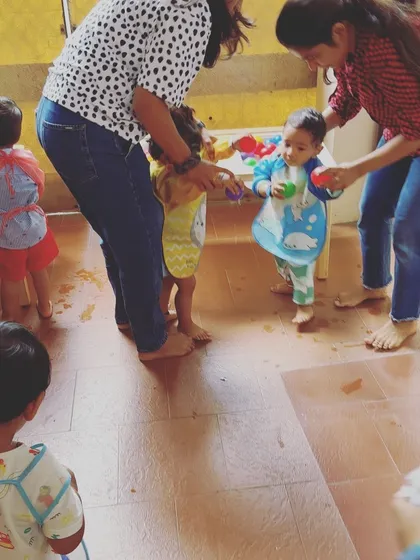 Our instructors are always on hand to guide and support the little ones. Here, toddlers are helped to stand and interact with the water table, ensuring a safe and positive gross motor and sensory experience.