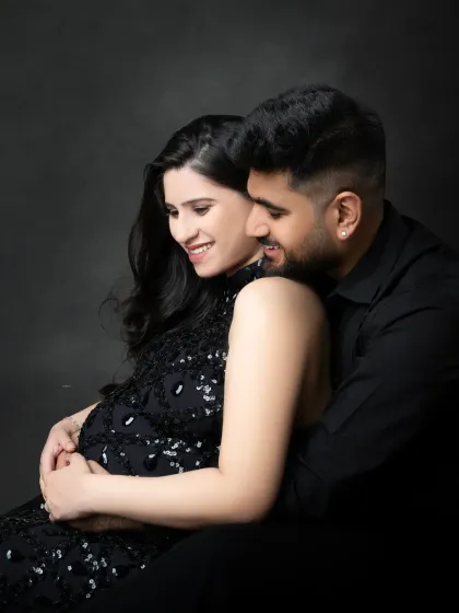 An intimate and loving embrace. This close-up shot in a dark studio setting highlights the couple's happy smiles and the secure feeling of being together.