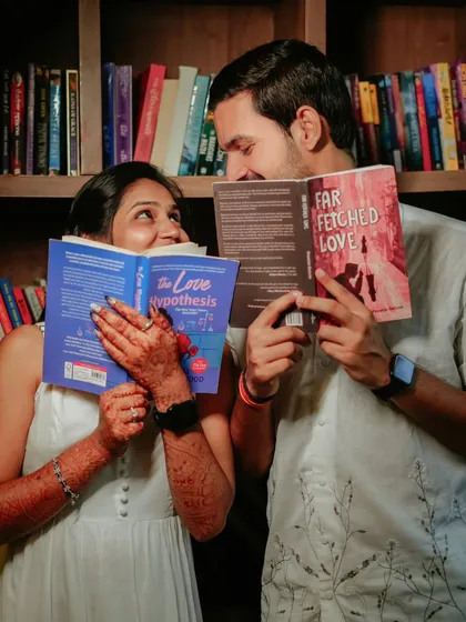 A playful and cute moment where the couple hides behind their books. This shot adds a touch of fun to their library-themed photoshoot.