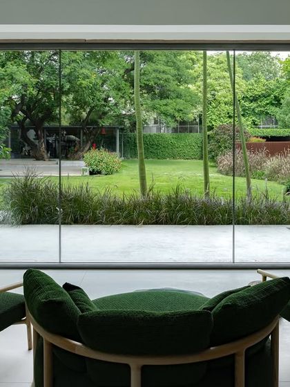 A serene coffee spot where the interior seating looks out onto an expansive lawn. The large, frameless window acts as a living painting, bringing the calmness of the minimalist landscape and its carefully selected native grasses indoors.
