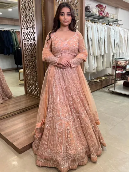 A full view of the peach lehenga, showing its graceful fall and the matching embroidered dupatta.