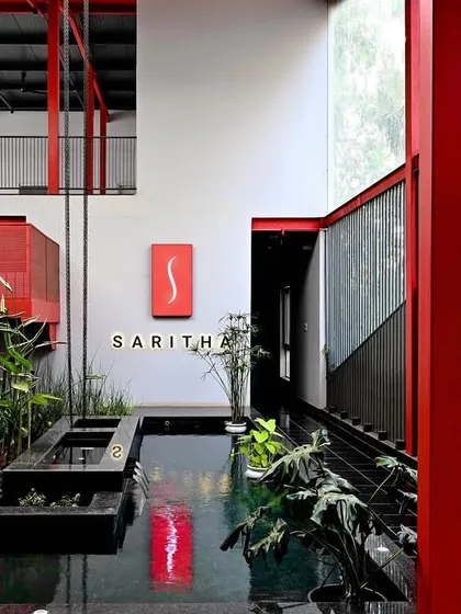 For the Saritha Serene marketing office, I used a bold red perforated staircase as a central sculptural element. It contrasts with the serene indoor water body and biophilic elements, creating a vibrant space that embodies the synthesis of industrial form and natural tranquility.