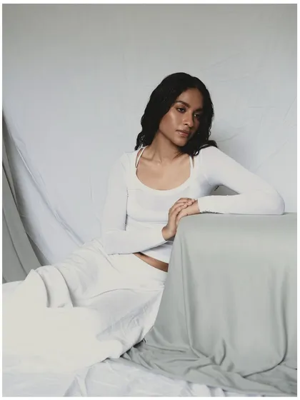 A wider shot from the all-white series, showing more of the draped fabric and setting. This gives context to the portraits and highlights the minimalist aesthetic of the shoot.