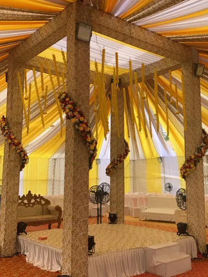 A closer look at the central stage inside the draped Haldi mandap. The pillars are decorated with floral garlands, and the seating is kept simple to maintain focus on the ceremony.