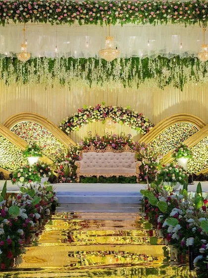 For a truly elegant reception, I designed this magnificent stage featuring cascading white flowers, sparkling chandeliers, and a stunning floral backdrop with gold-accented panels. This premium stage design is perfect for a grand wedding celebration.