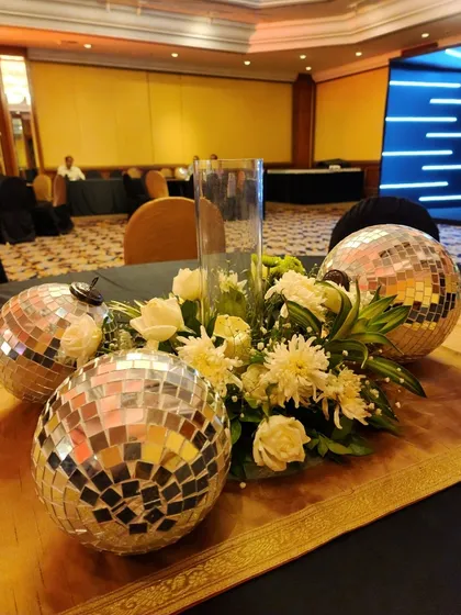 A close-up of a modern centerpiece combining white florals with mirrored disco balls. This is a fun and stylish way to carry the party theme through to the guest tables.