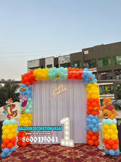 A classic Winnie the Pooh theme for a first birthday. This colorful outdoor setup includes character cutouts of Pooh and Tigger against a balloon arch.