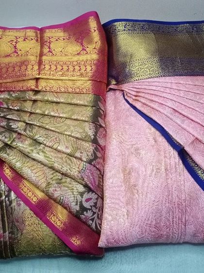 Two beautiful silk sarees, pleated and ready for a client. One is a floral brocade, and the other is a soft pink, showing the versatility of my service.