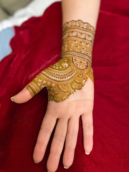 The design is extended to the thumb with detailed filler work. This shows how to seamlessly integrate finger designs with the main pattern on the hand.