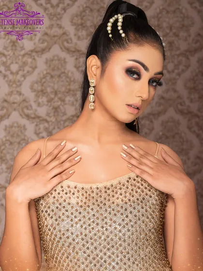 A golden goddess look. This style features a dramatic smokey eye, a sleek high ponytail, and a shimmering gold top, perfect for a night out.