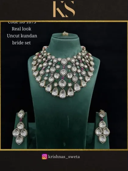 A real-look uncut Kundan bridal set with ruby and emerald accents. The design features multiple rows of large, sparkling stones.