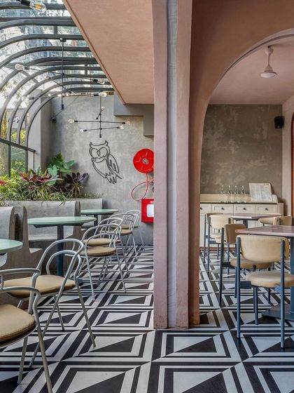 A similar view of the conservatory-style seating at Hangover. The combination of graphic flooring, exposed concrete, and lush plants creates a modern yet comfortable atmosphere.