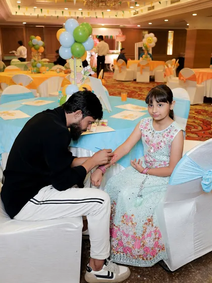 A young guest getting her arm painted at a face and body art station during a Winnie the Pooh themed party.