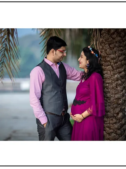 A relaxed and romantic pose, with the couple leaning against a palm tree and sharing a moment.