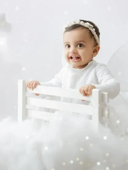 A little fairy in the clouds. This dreamy, all-white setup with soft clouds and sparkling lights creates a magical, heavenly portrait.