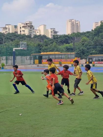 Players from two houses run across the field during a fast-paced football game. The tournament fosters a healthy sense of competition and house spirit among the students.