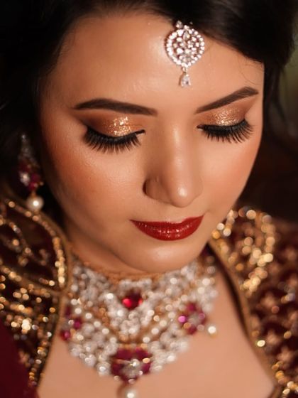 A classic and dramatic reception look. The combination of bold gold glitter on the eyes and a deep red lip creates a statement of pure glamour and confidence.