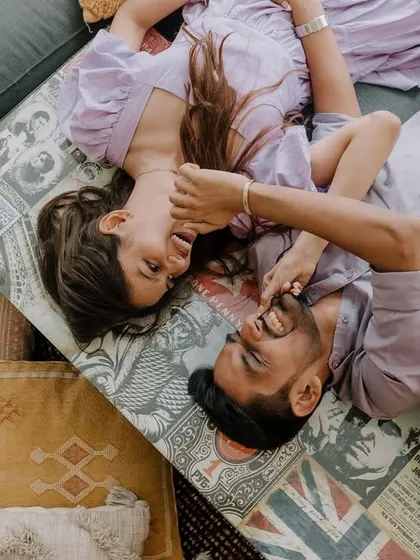 A cozy and intimate overhead shot of a couple lying amidst pillows. This playful and relaxed portrait from their Goa shoot captures a feeling of comfort and closeness.