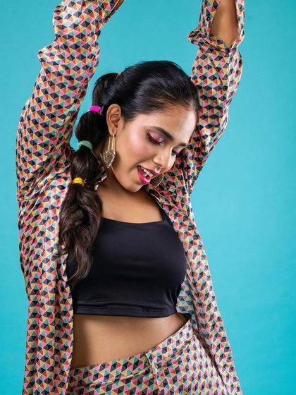 A fun and colorful makeup look for a fashion shoot. The bright pink eyeshadow and bubble ponytail create a youthful and energetic vibe that matches the quirky outfit.