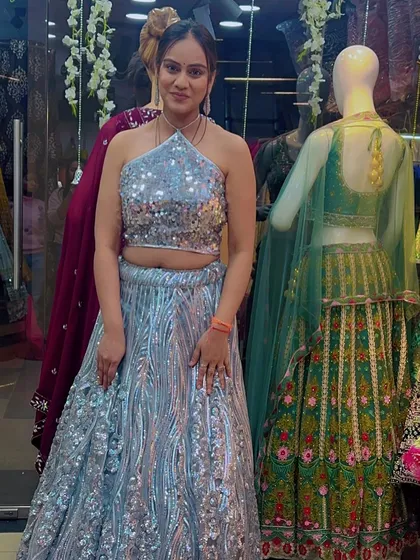 A client trying on a stunning light blue lehenga covered in silver sequins. The halter neck blouse adds a modern touch to this sparkling ensemble.
