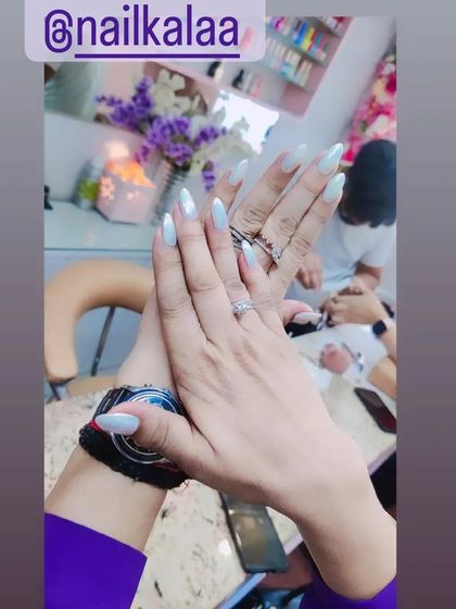 A simple and elegant set of long, almond-shaped nails in a pearlescent white. This is a timeless and chic choice.