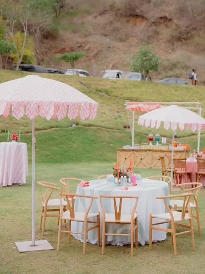 A charming outdoor seating arrangement with a custom-printed umbrella, perfect for a sunny afternoon event.