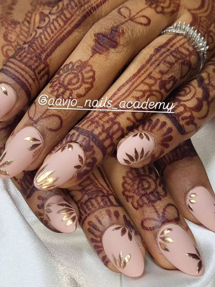 This angle showcases how the golden leaves catch the light against the soft nude polish. It's a perfect example of how I can match your nails to your jewelry and wedding attire.