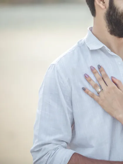 A detail shot focusing on the bride's hand with her engagement ring, resting on the groom's chest. A simple, elegant, and meaningful photograph.