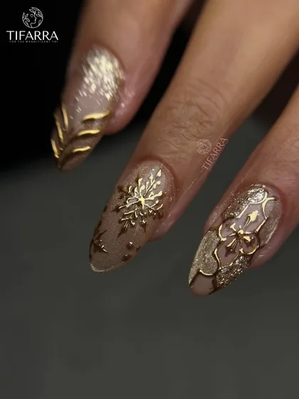 A complete view of our golden snowflake and filigree nail art set. Each nail features a different hand-sculpted design for a cohesive yet varied look.