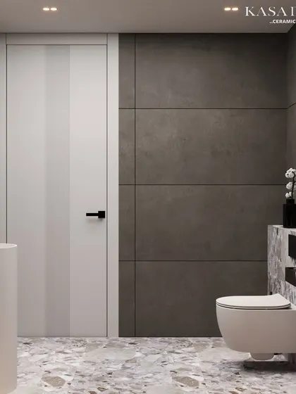 This view shows how different surface materials work together in a modern washroom. The terrazzo-style floor and wainscoting are balanced by the dark, concrete-look wall tiles and a clean, white door.