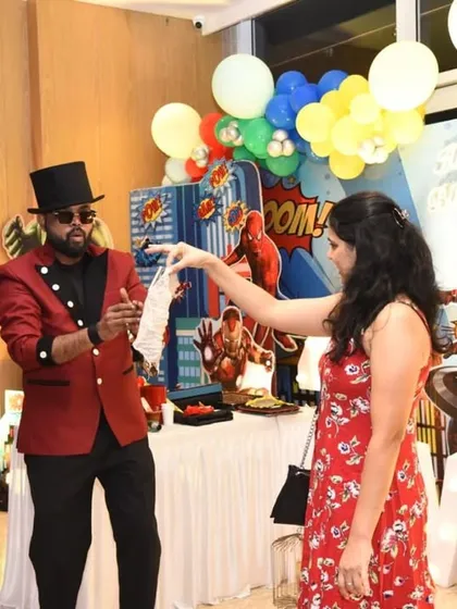 An adult guest participates in a classic silk handkerchief trick at a superhero themed party. It's always fun to see the surprise on the faces of the grown-ups.