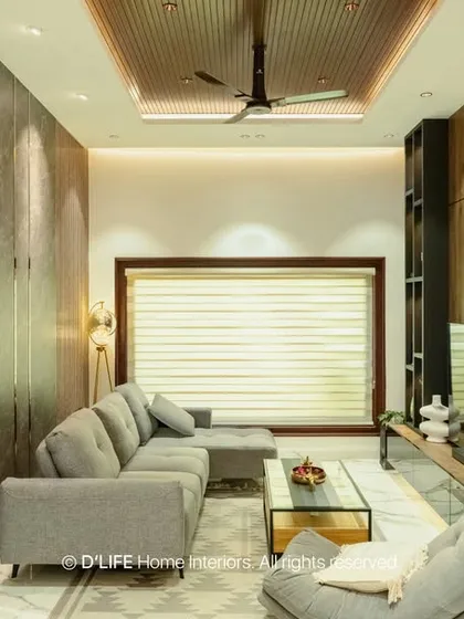 A modern living room with a comfortable grey sectional sofa, dark wood paneling, and a custom shelving unit. The design is both stylish and functional, perfect for contemporary living.