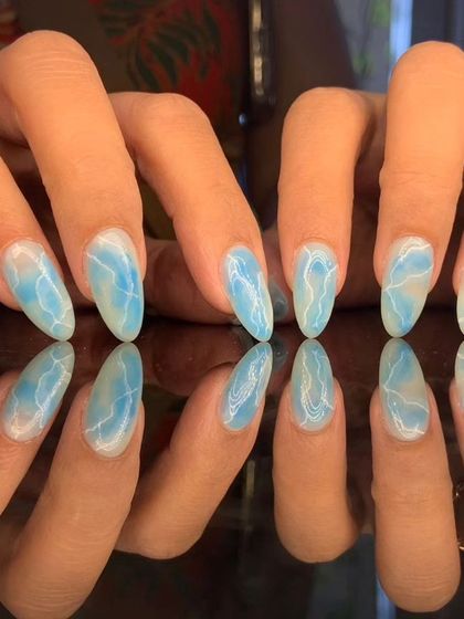 A beautiful blue and white marble or water-like effect on long almond nails.