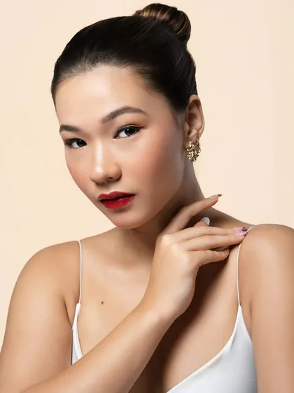 A portrait showcasing the complete look: a sleek, high bun, flawless skin, and the statement red lip and wing. It's a look of pure, timeless sophistication.