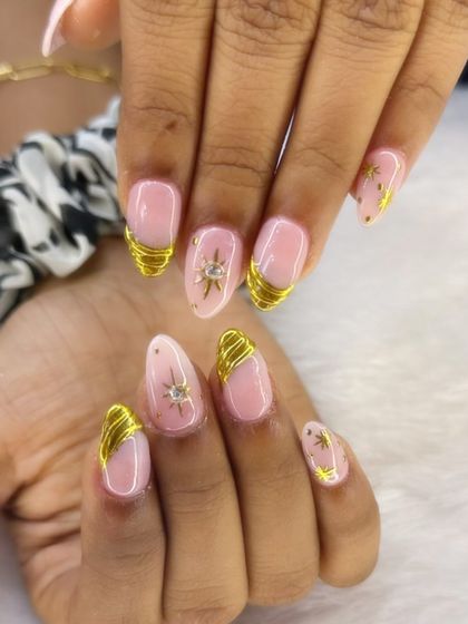 A chic and stylish set featuring a nude base with wrapped gold chrome accents. The hand-painted gold starbursts with rhinestone centers add a touch of celestial glamour.