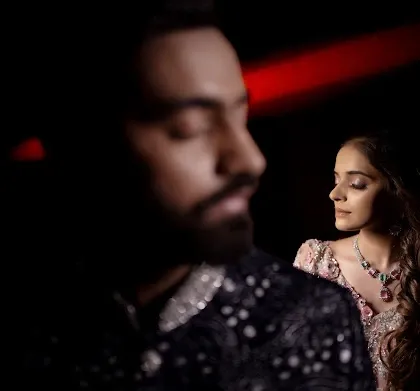 A creative portrait using selective focus. The groom is blurred in the foreground, drawing all the attention to the bride's serene expression in the background. It tells a story of love and perspective.