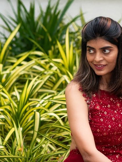 A candid portrait taken against a backdrop of lush greenery. The natural light and setting create a soft and beautiful image.