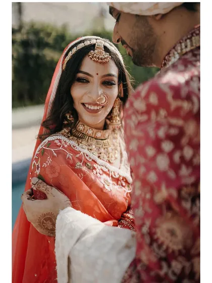 A close-up shot filled with happiness. The bride's radiant smile is the focus as she shares an intimate moment with her groom on their wedding day.