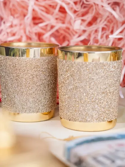 These golden glitter candle jars are a glamorous option for wedding favors or party decor, available for bulk orders.
